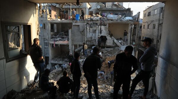 Палестинцы осматривают разрушения жилых зданий после авиаударов Израиля