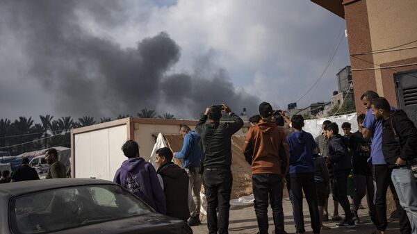 Палестинцы смотрят на дым после авиаудара Израиля 