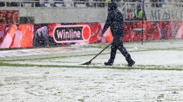 Сотрудник стадиона очищает поле от снега