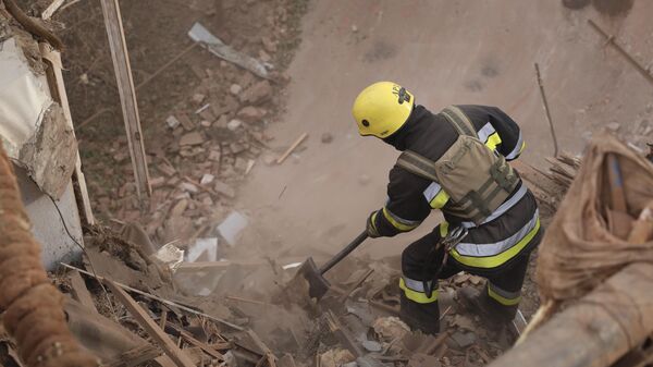 Сотрудник МЧС Украины разбирает завалы на месте обрушения здания