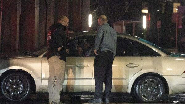 Сотрудники правоохранительных органов разговаривают с водителем автомобиля, который врезался в машину рядом с автоколонной американского президента Джо Байдена