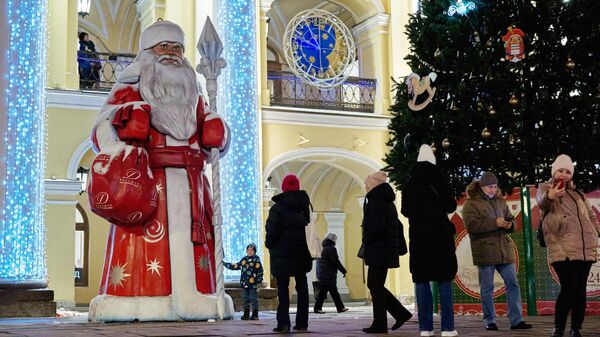 Люди фотографируются на фоне фигуры Деда Мороза в Большом гостином дворе в Санкт-Петербурге