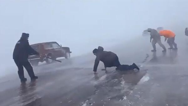 Кадр видео с ползущими по ледяной дороге людьми