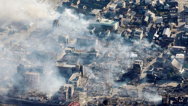Дым над зданиями после сильного пожара в городе Вадзима, префектура Исикава в Японии. 2 января 2024