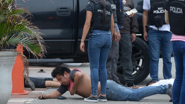 Сотрудники эквадорской полиции охраняют арестованных подозреваемых у здания эквадорского телеканала TC Television после того, как неизвестные вооруженные люди ворвались на съемочную площадку во время прямого эфира в Гуаякиле, Эквадор