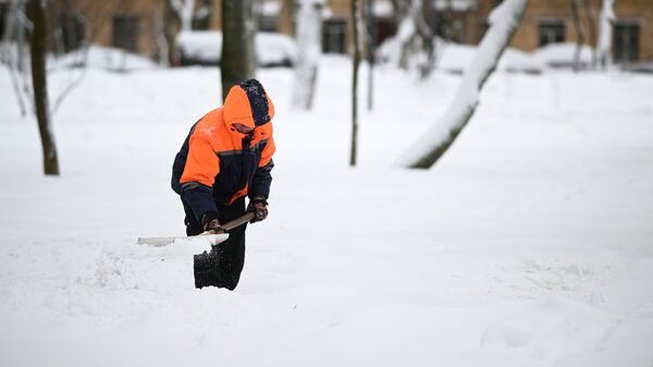 Сотрудник коммунальной службы убирает снег на улице в Москве