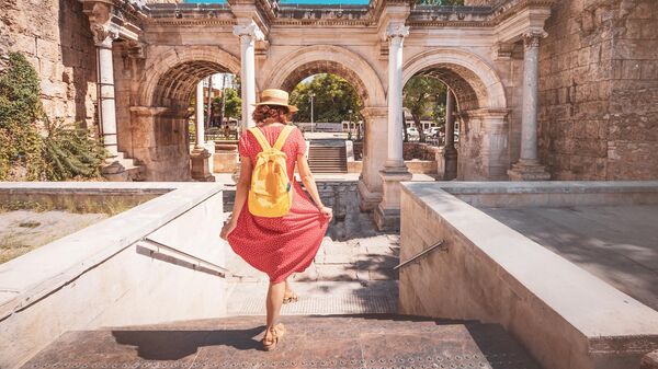 Женщина гуляет по старому городу Антальи на фоне римских ворот Адриана