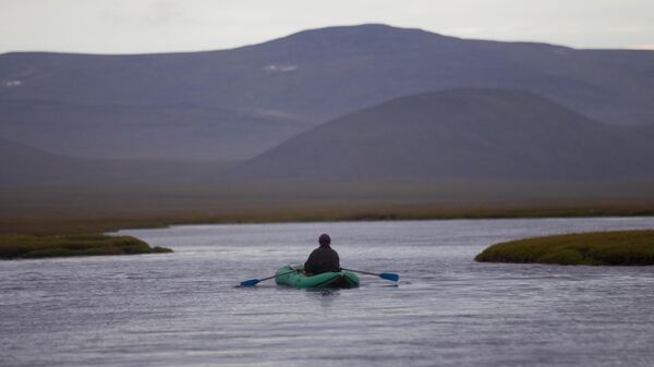 Человек плывет на надувной лодке в окрестностях села Лорино Чукотского района Чукотского автономного округа