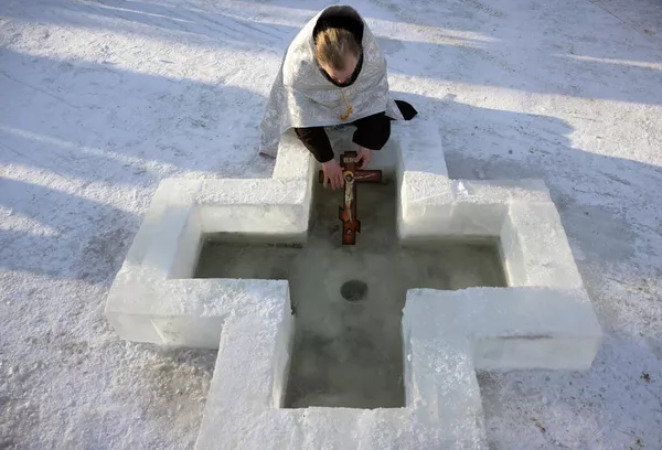 ノボシビルスク地方ベルツク市で公現祭の沐浴中に祝福の水の儀式を行う司祭