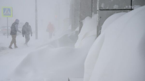 Люди на одной из улиц Южно-Сахалинска во время снегопада