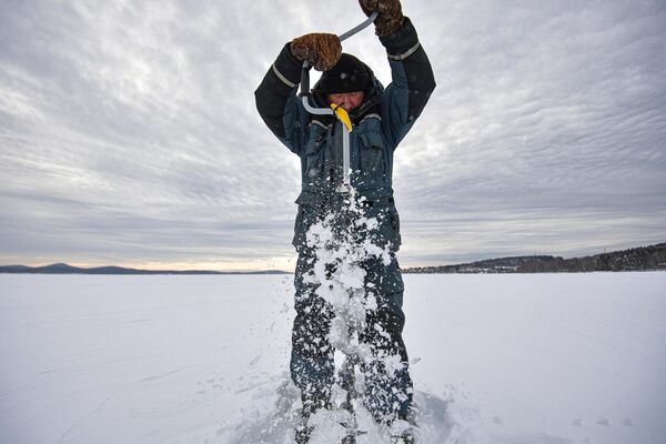 Рыбак сверлит лунку для рыбалки на озере Таватуй в Свердловской области