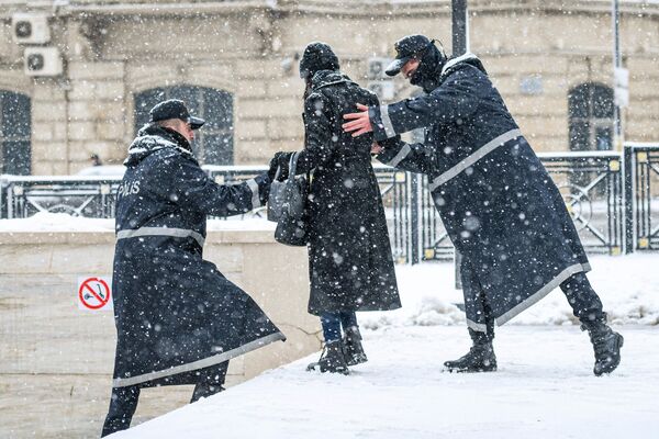 Полицейские помогают девушке спуститься по лестнице во время снегопада в Баку