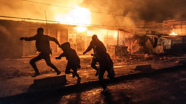 Люди спасаются от пожара, начавшегося в районе Эмбакаси в Найроби, Кения