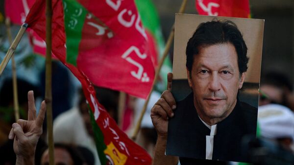 Сторонники партии Движение за справедливость с портретом Имрана Хана во время митинга с требованием досрочных выборов в Карачи
