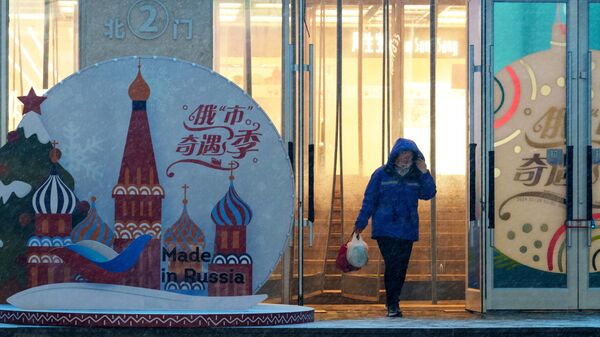 Женщина выходит из торгового центра в городе Шеньян, где проходит ярмарка Сделано в России