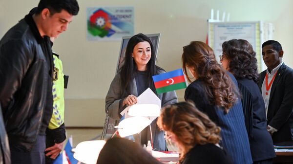 Женщина получает бюллетень для голосования на внеочередных выборах президента Азербайджана на избирательном участке в Баку