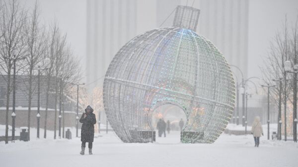 Человек идет во время снегопада по улице в Москве