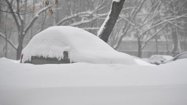 Машина, запорошенная снегом, стоит на парковке в Москве