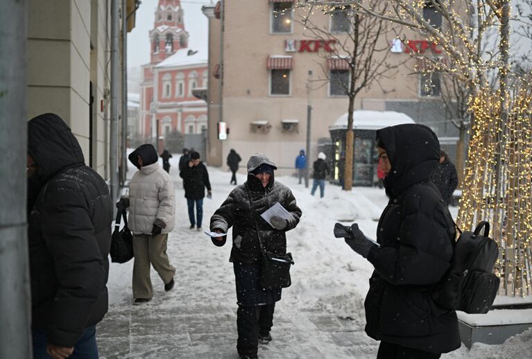 Мужчина раздает листовки во время снегопада в Москве