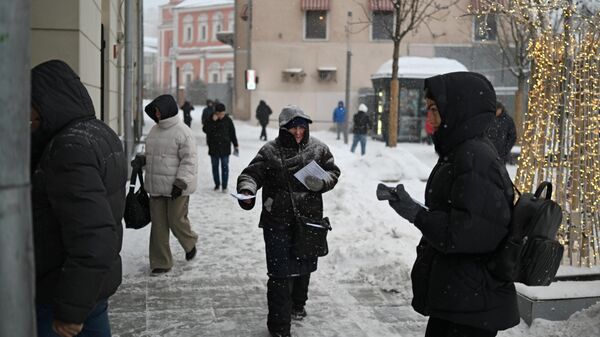 Мужчина раздает листовки во время снегопада в Москве