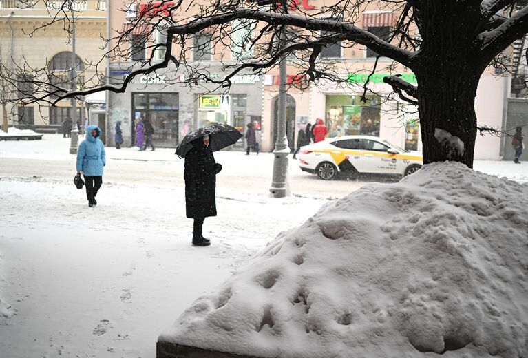 Люди во время снегопада на улице Москвы