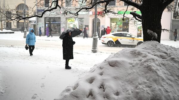 Люди во время снегопада на улице Москвы