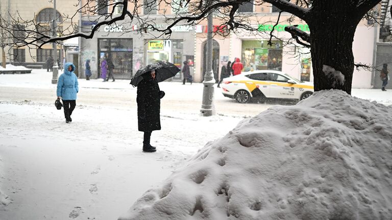 Люди во время снегопада на улице Москвы