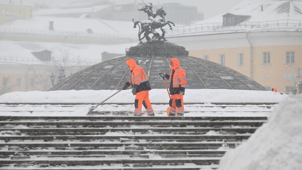 Сотрудники коммунальной службы убирают снег на Манежной площади во время снегопада в Москве