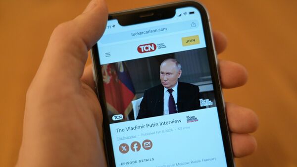 Интервью Владимира Путина американскому журналисту Такеру Карлсону на экране телефона