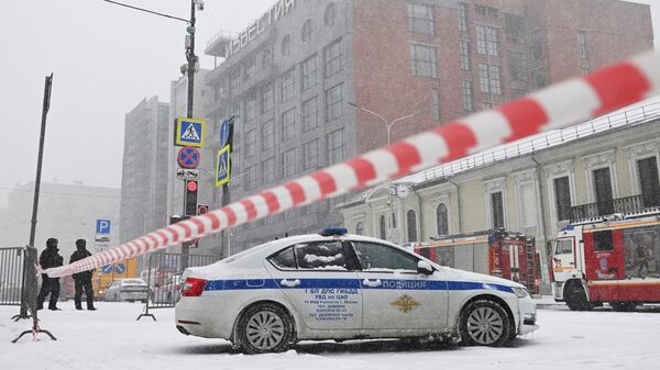 Сотрудники полиции и автомобили спецслужб у здания, где произошел пожар, на Пушкинской площади в Москве