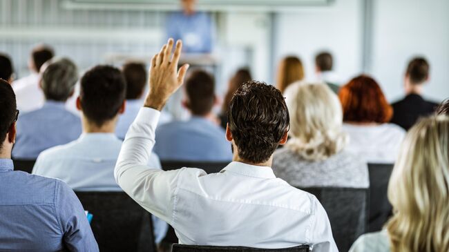 Бизнесмен поднимает руку во время семинара
