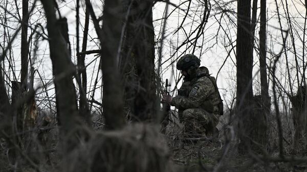 Украинский военнослужащий рядом с колесной самоходной гаубицей