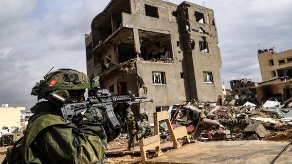 Израильский солдат перед разрушенным зданием в Хан-Юнисе