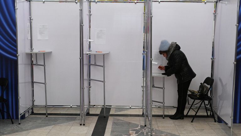 Женщина голосует на выборах депутатов нижней палаты парламента и местных советов Белоруссии на избирательном участке в Минске
