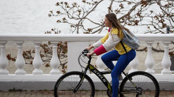 Девушка на велопрогулке по набережной в Геленджикской бухте.