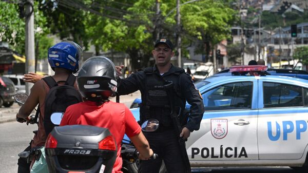 Сотрудник полиции дает инструкции мотоциклистам у одного из входов в фавелу во время полицейской операции в Рио-де-Жанейро. 27 февраля 2024