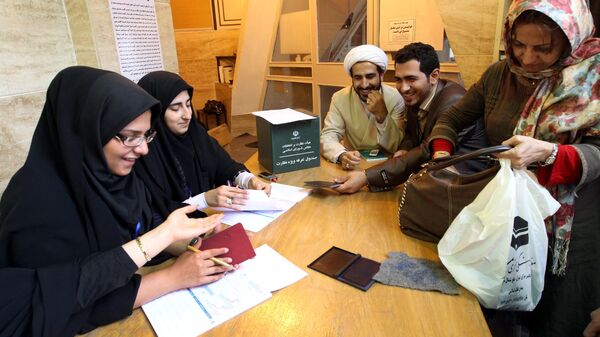 Иранский избирательный штаб проверяет удостоверение личности избирателя в мечети в Тегеране во время второго тура парламентских выборов 4 мая 2012 года
