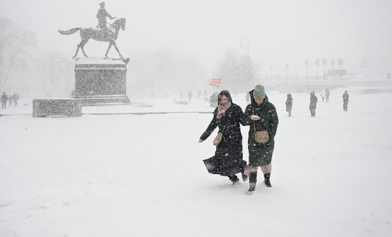 Люди на Манежной площади во время снегопада в Москве