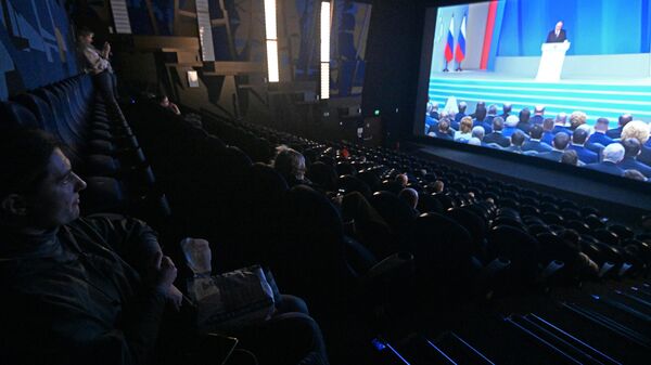 Люди смотрят трансляцию ежегодного послания президента РФ Владимира Путина к Федеральному Собранию в кинотеатре Балтика в ТРЦ Калейдоскоп в Москве