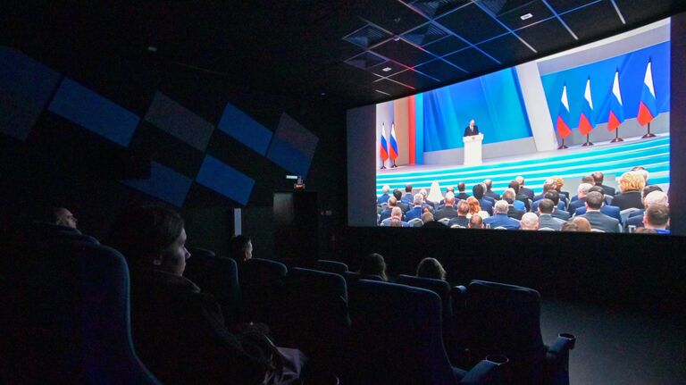 Люди смотрят трансляцию ежегодного послания президента РФ Владимира Путина к Федеральному Собранию в кинотеатре в ТРК Шкиперский молл в Санкт-Петербурге