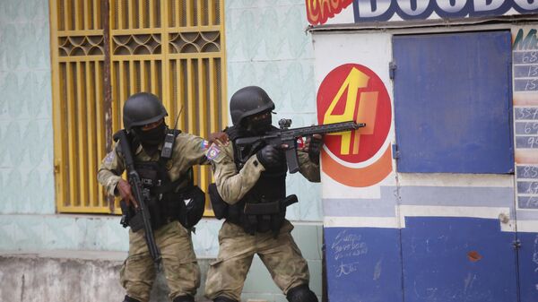 Полиция укрывается во время операции по борьбе с бандами в городе Порт-о-Пренса в Гаити. 1 марта 2024