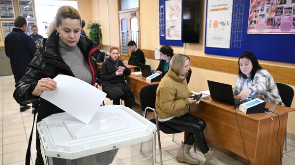 Женщина опускает бюллетень в урну во время тестового голосования перед выборами президента РФ на избирательном участке в московской школе № 354 имени Д. М. Карбышева. 2 марта 2024 года