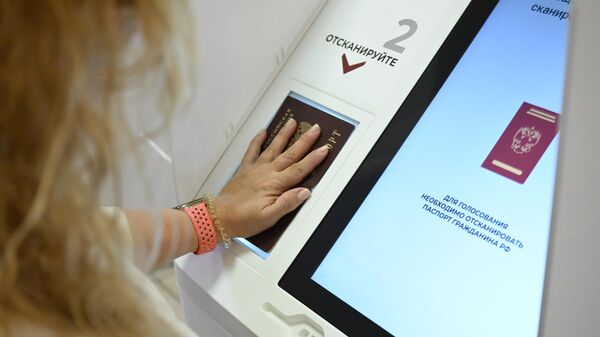 Женщина сканирует паспорт во время тестового голосования перед выборами президента РФ на избирательном участке в московской школе № 354 имени Д. М. Карбышева