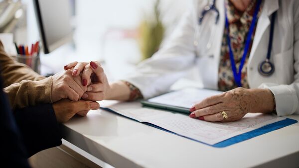 Врач держит за руку пациента во время консультации