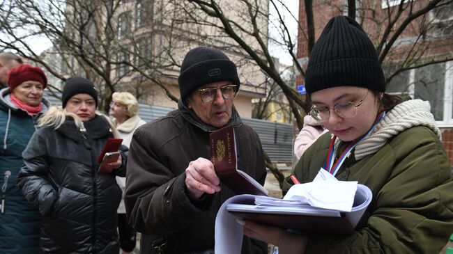 Член избирательной комиссии регистрирует жителей на выездном голосовании в Донецке в первый день досрочного голосования на выборах президента РФ в ДНР. 10 марта 2024