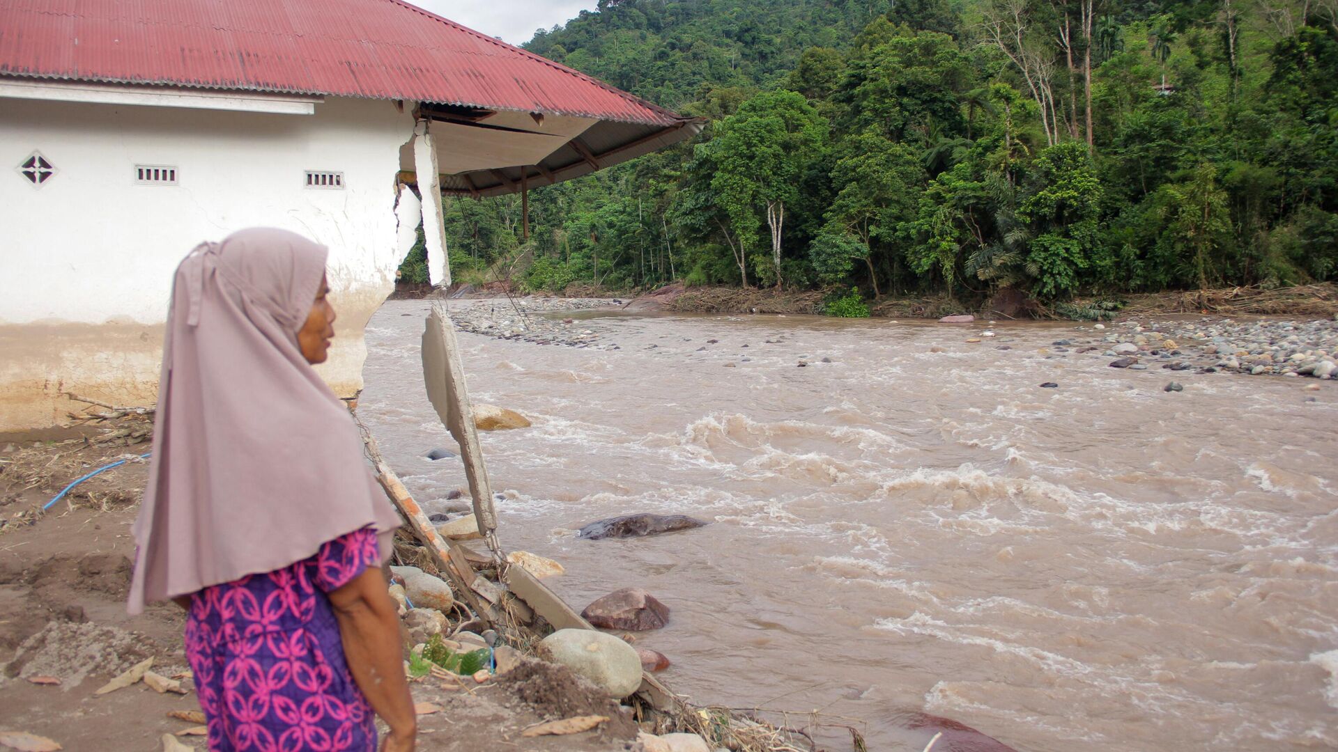 Женщина стоит возле поврежденного дома после наводнения в индонезийской провинции Западная Суматра. 10 марта 2024 - РИА Новости, 1920, 11.03.2024