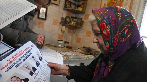 Жительница города изучает избирательный бюллетень на выездном голосовании в Северодонецке в первый день досрочного голосования на выборах президента РФ в ЛНР