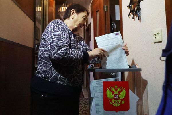 Женщина голосует на выездном голосовании в первый день досрочного голосования на выборах президента РФ в поселке Дубовое Белгородской области
