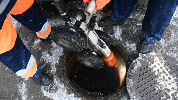 Сотрудники Мосводоканала опускают в канализационный люк роботизированную технику для проведения профилактико-ремонтных работ