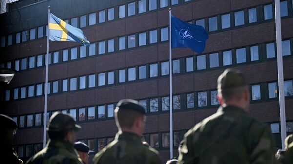 Шведские военные во время церемонии поднятия флага НАТО перед штабом вооруженных сил Швеции в Стокгольме